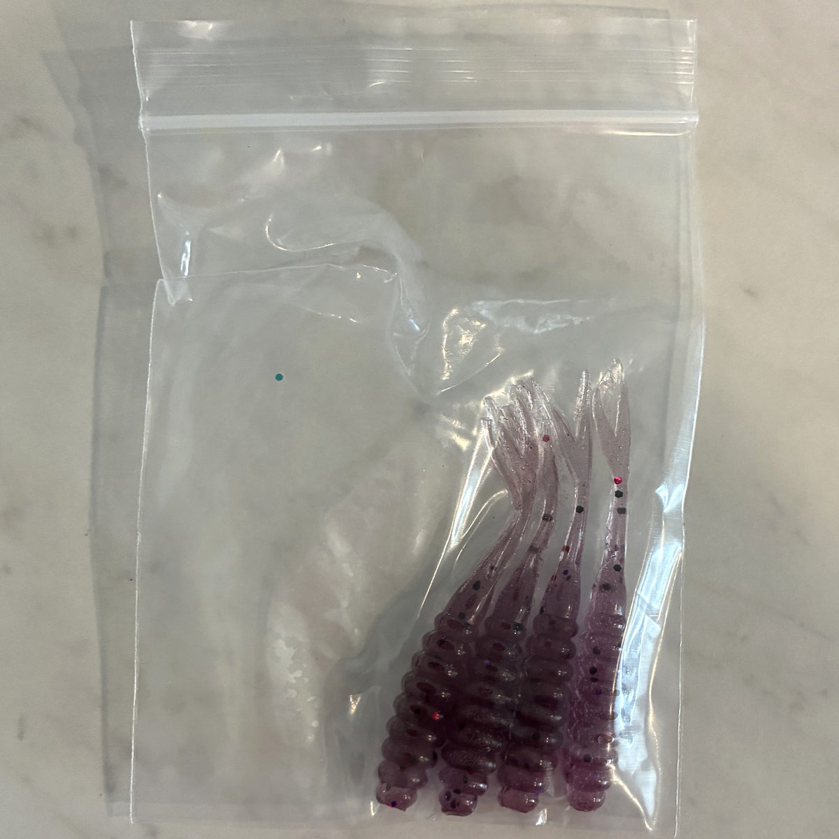 Four hand-poured purple ribbed split tail baits with flake